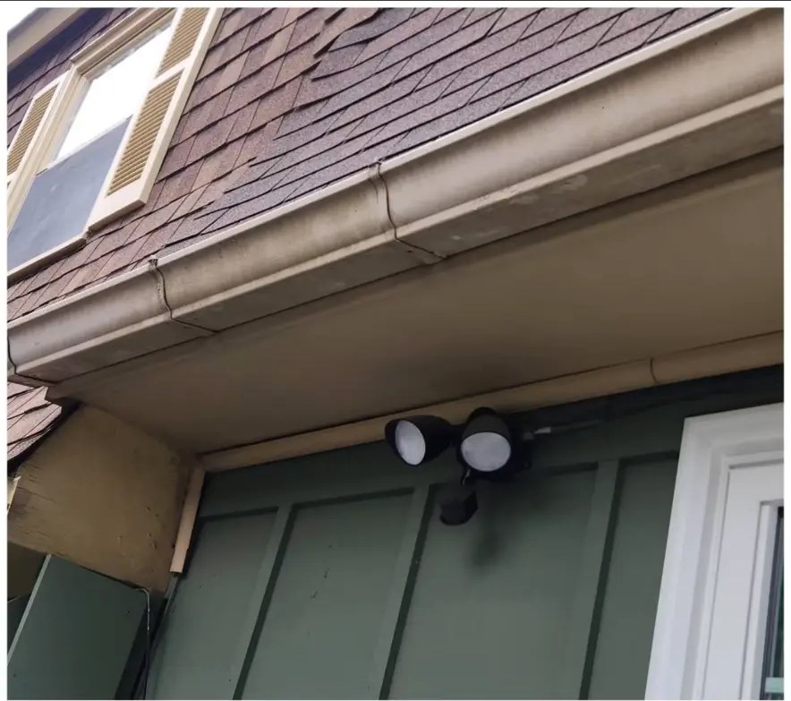 Before: dingy tan gutters, soffit, and fascia on a green-sided home