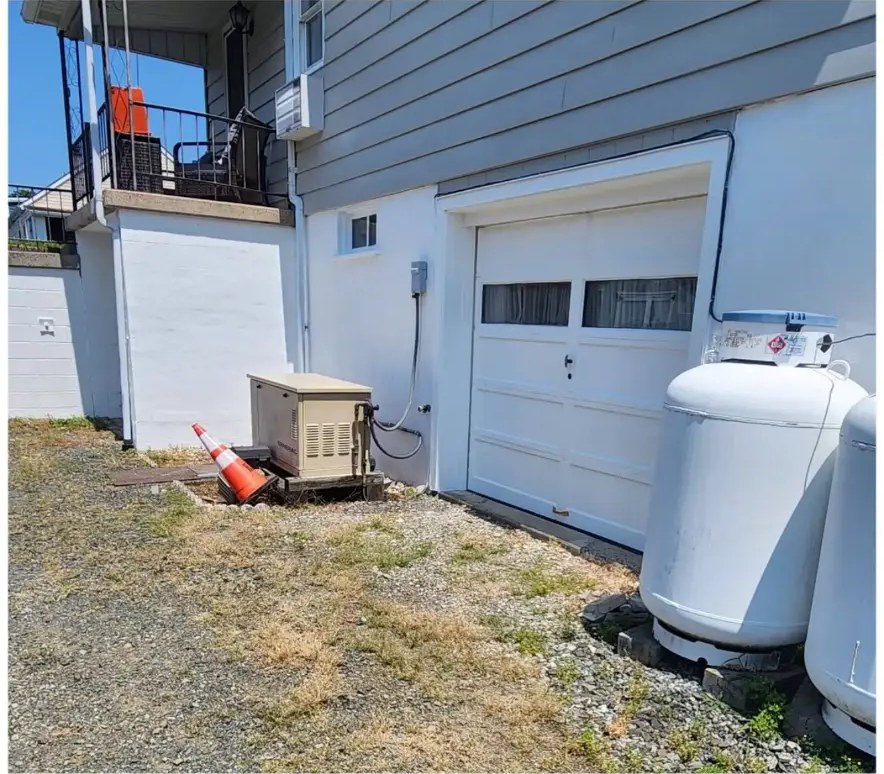 After exterior painting: clean white block and siding near a garage and generator