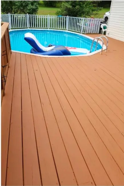 After pool deck staining: rich warm-brown boards around an above-ground pool