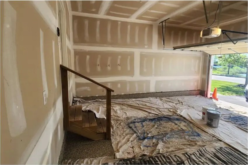 Before: unfinished wood garage stairs and handrail with bare drywall around them